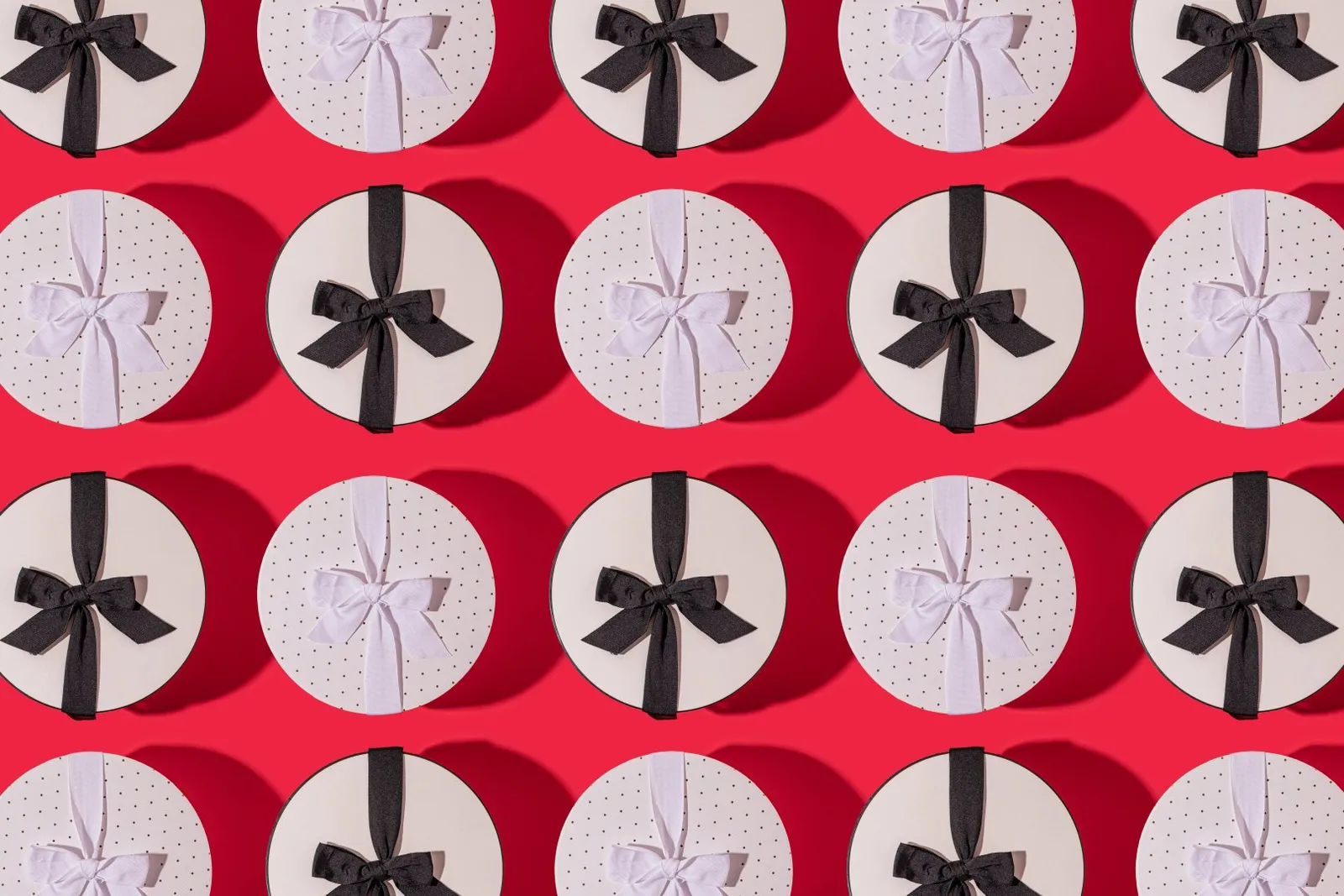 Rows of small, round gift boxes each with a black or white ribbon.